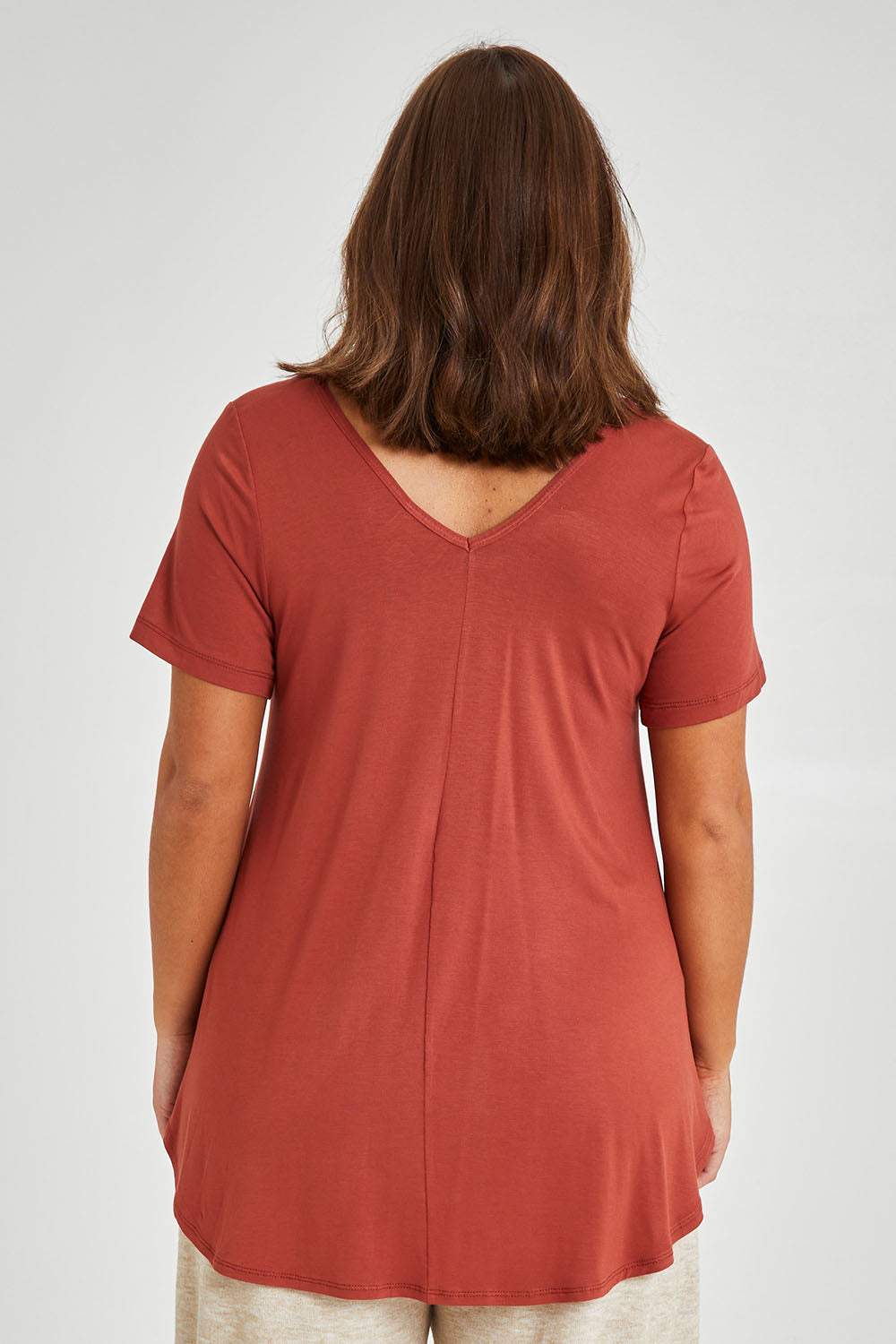 Model Monique wearing size 14 of the Softly Swinging Bamboo Tee in colour Clay (Red), from the back
