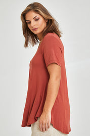 Model Monique wearing size 14 of the Softly Swinging Bamboo Tee in colour Clay (Red), from the front, cropped image
