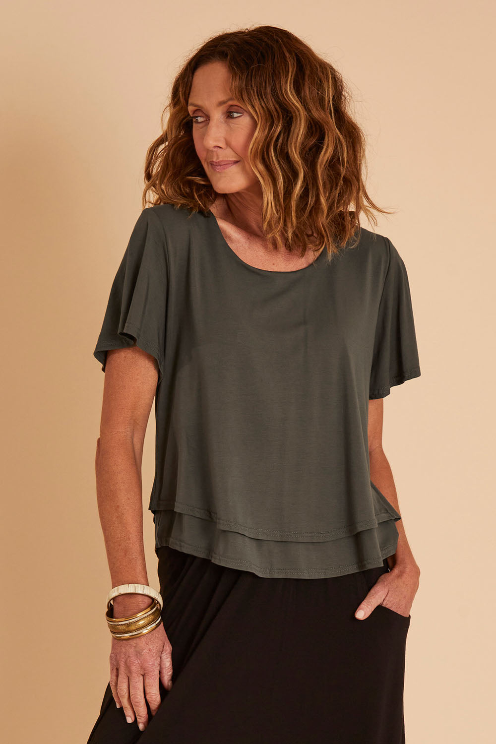 Model Emma wearing size 10 of the Short And Sweet Bamboo Layered Tee in colour Combat (Green), from the front, cropped image