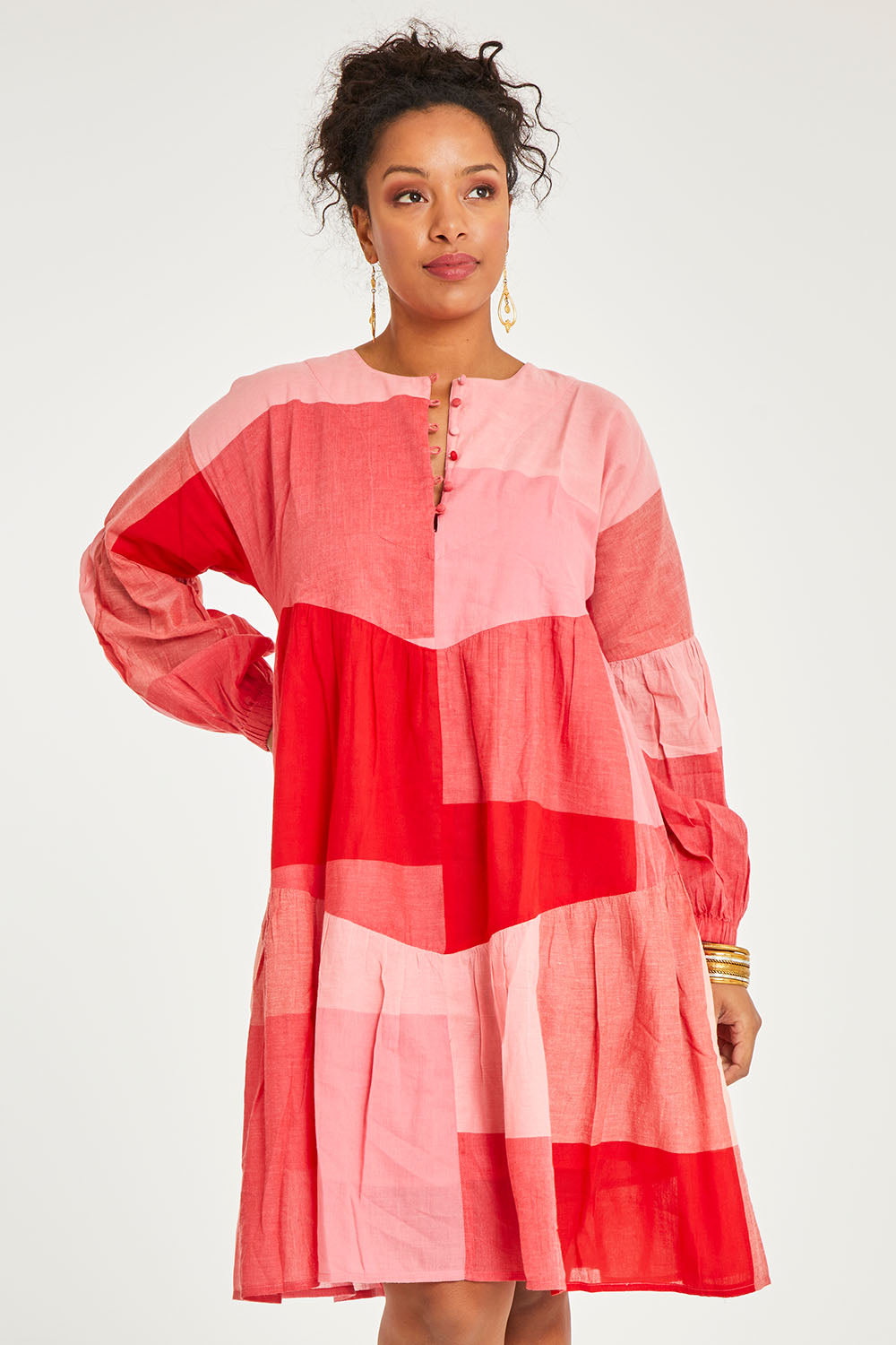 Model Noli wearing the Twirl Worthy Cotton Tiered Dress in colour Redpink (Pink), from the front, cropped image