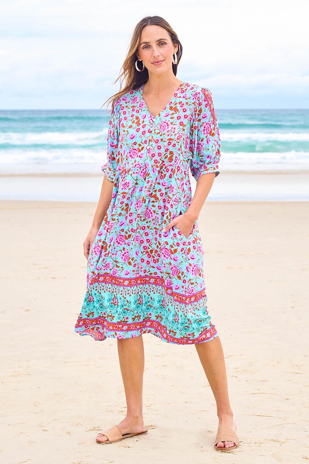 Model Tegan wearing size 10 of the Sunshine And Flowers Smock Dress in colour Aquafleur (Blue), from the front, showing the whole outfit