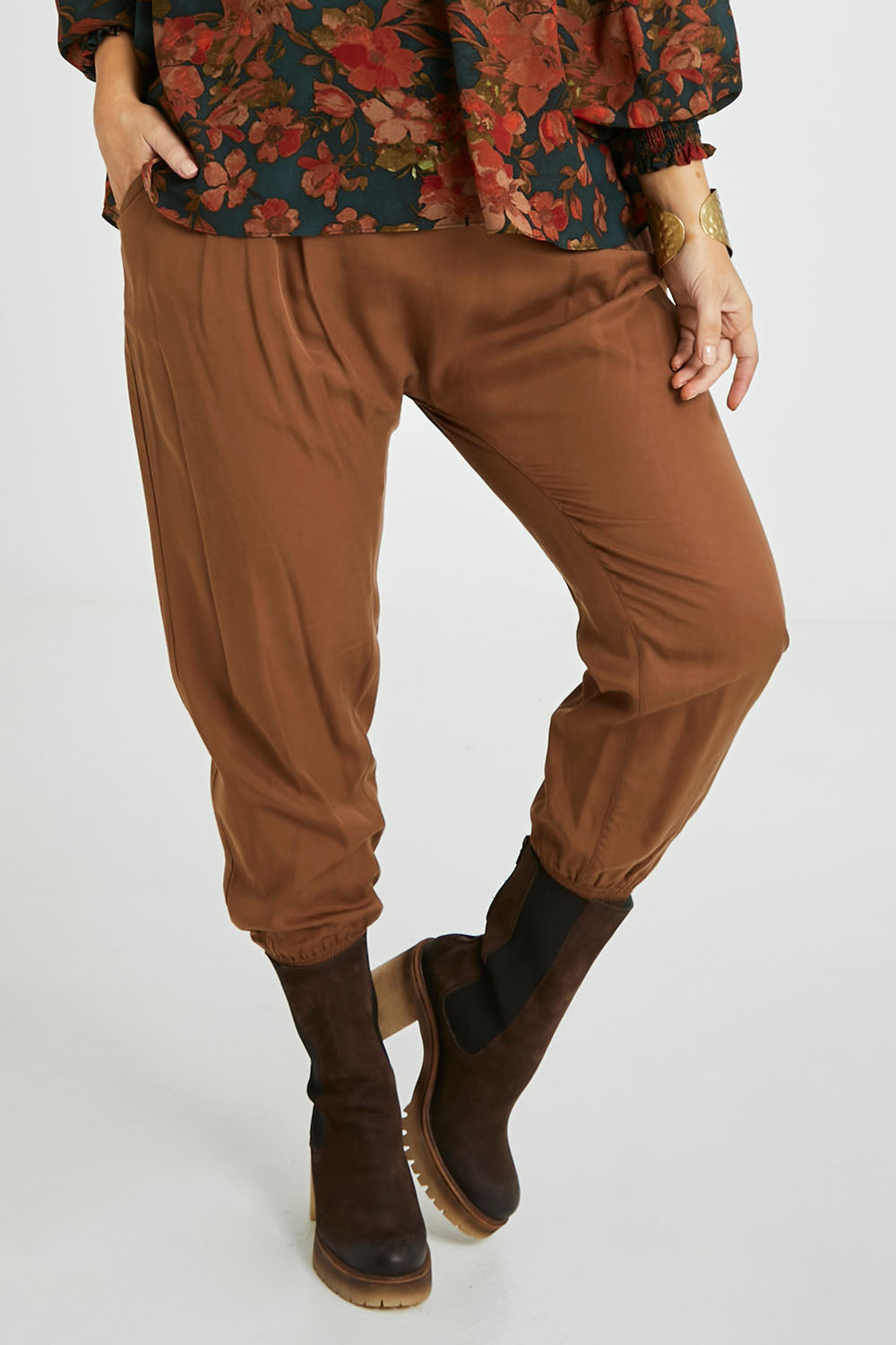 Model Laura wearing size 14 of the Brunch and Dinner Tencel Pants in colour Rust, from the front, cropped image