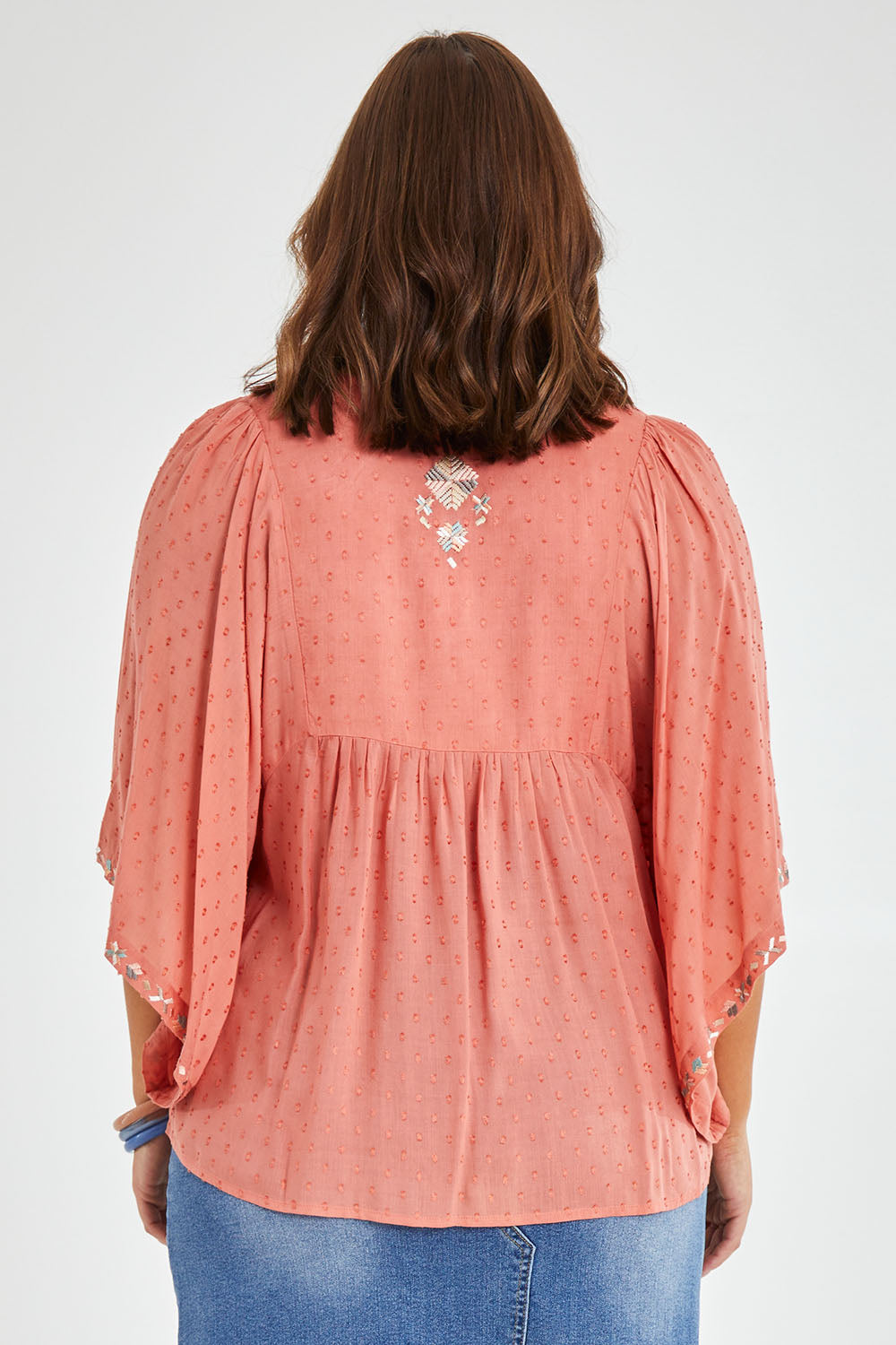 Model Monique wearing size 14 of the Simple Things Embroidered Top in colour Peach (Pink), from the back