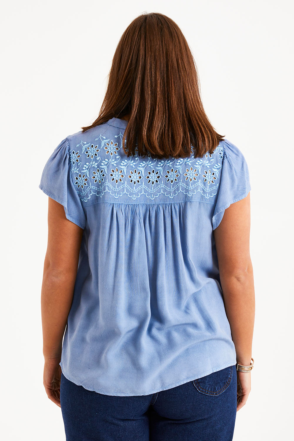 Model Monique wearing size 14 of the Floral Fields Embroidered Top in colour Chambray (Blue), from the back