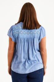 Model Monique wearing size 14 of the Floral Fields Embroidered Top in colour Chambray (Blue), from the back