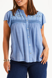 Model Monique wearing size 14 of the Floral Fields Embroidered Top in colour Chambray (Blue), from the front, cropped image
