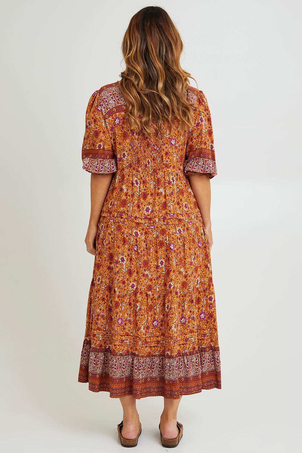 Model Laura wearing size 14 of the Paradise Found Maxi Dress in colour Rustfleur, from the back