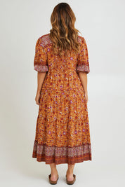 Model Laura wearing size 14 of the Paradise Found Maxi Dress in colour Rustfleur, from the back