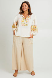 Model Monique wearing size 14 of the Serene Day Wide Leg Pants in colour Sand, from the front, showing the whole outfit