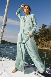Model Tegan wearing size 10 of the Going With The Flow Tunic Blouse in colour Sage (Green), from the front, showing the whole outfit