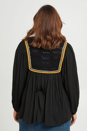 Model Monique wearing size 14 of the Ebb And Flow Crochet Detail Top in colour Black (Black), from the back