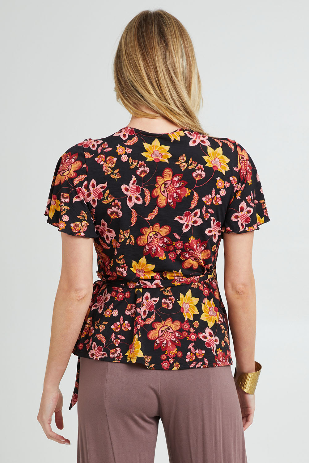 Model Grace wearing size 10 of the All For You Wrap Top in colour Blkfleur (Black), from the back