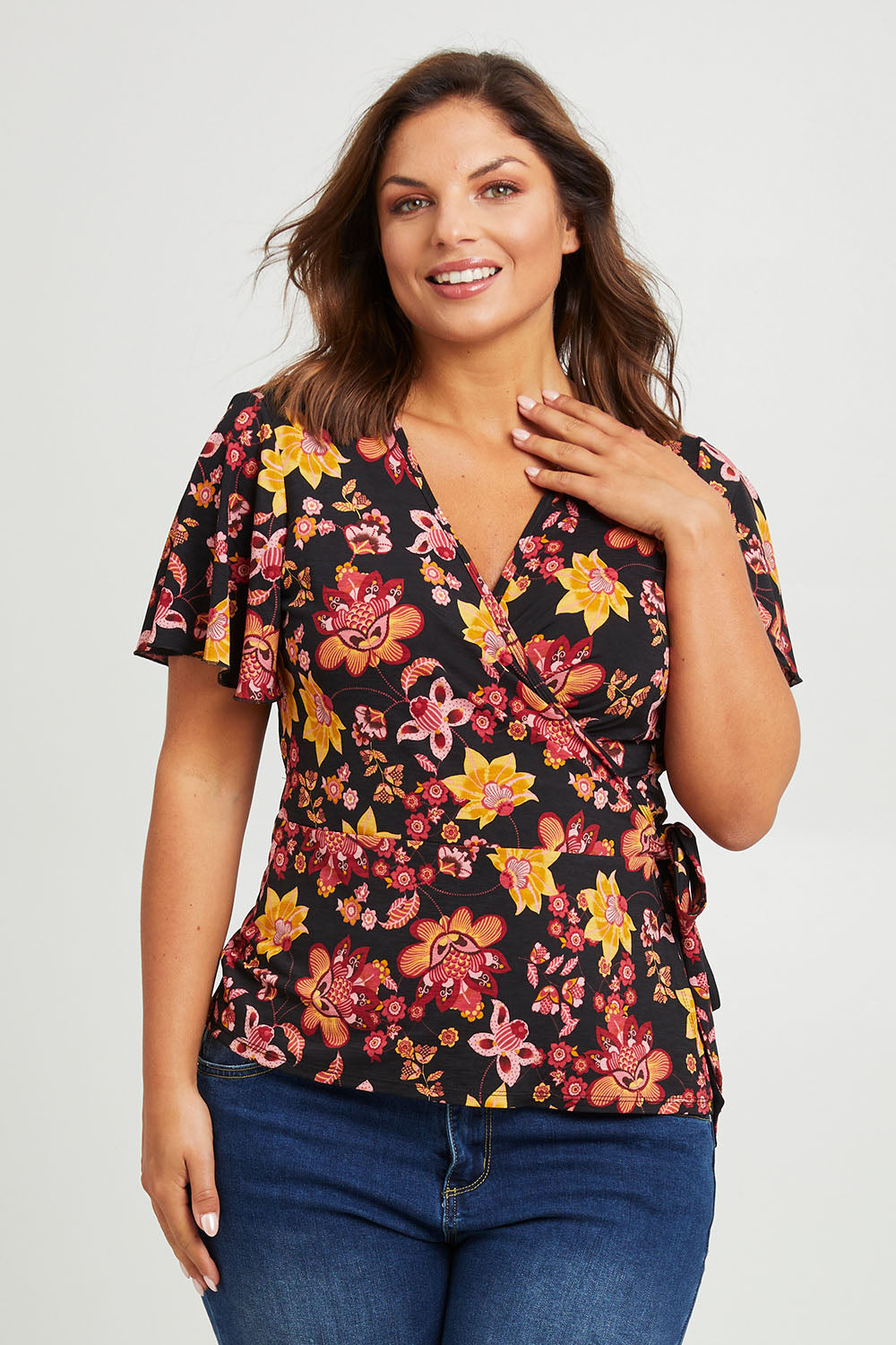 Model Monique wearing size 14 of the All For You Wrap Top in colour Blkfleur (Black), from the front, cropped image