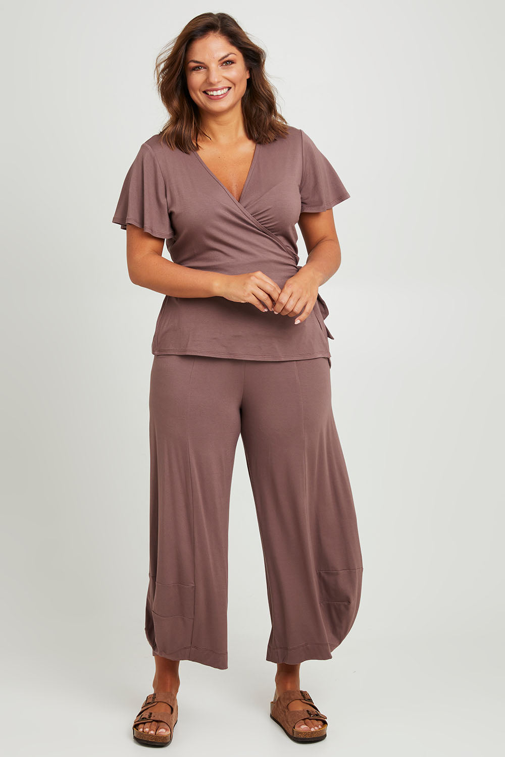 Model Monique wearing size 14 of the All For You Wrap Top in colour Tobacco, from the front, showing the whole outfit