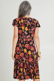 Model Luisa wearing size 10 of The Frill You Give Me Dress in colour Blkfleur (Black), from the back