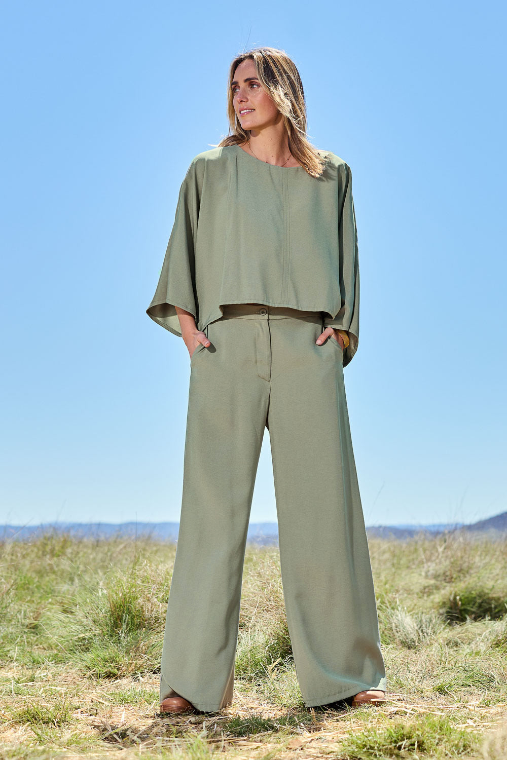Model Tegan wearing size 10 of the Striding Out Wide Leg Pants in colour Thyme (Green), from the front, showing the whole outfit