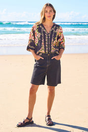 Model Tegan wearing size 10 of the Daily Dose Longline Denim Shorts in colour Black (Black), from the front, showing the whole outfit