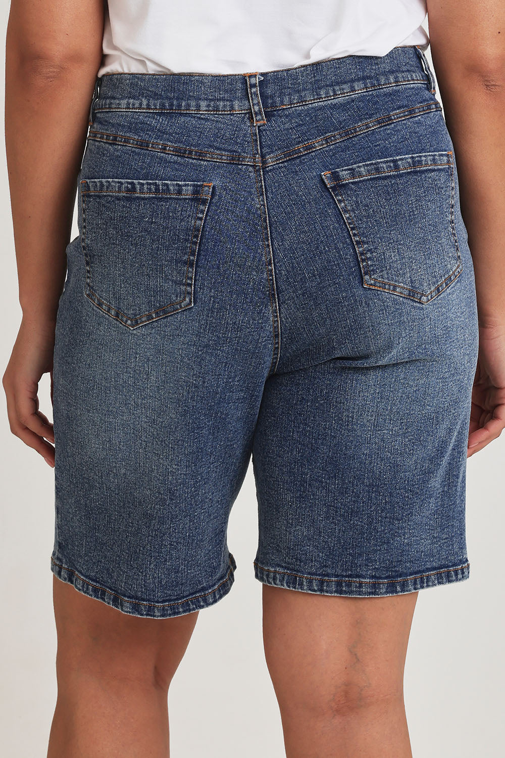 Model Terri-Leigh wearing size 14 of the Daily Dose Longline Denim Shorts in colour Denim (Blue), from the back