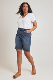 Model Terri-Leigh wearing size 14 of the Daily Dose Longline Denim Shorts in colour Denim (Blue), from the front, showing the whole outfit