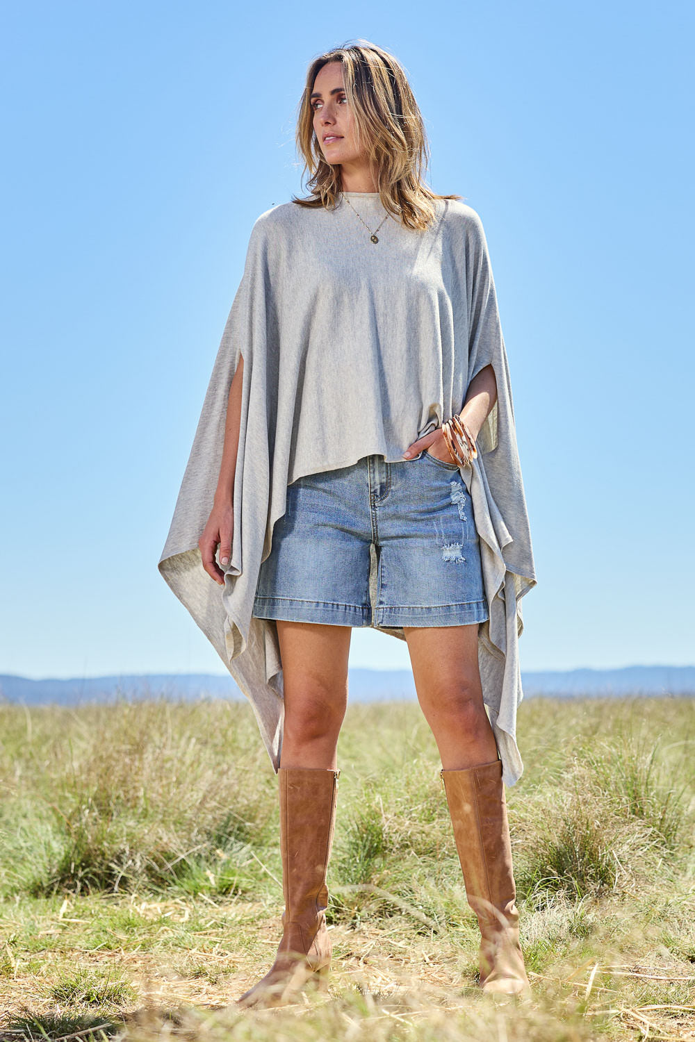 Model Tegan wearing the Light Breeze Poncho in colour Mist (Grey), from the front, showing the whole outfit