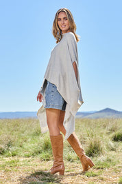 Model Tegan wearing the Light Breeze Poncho in colour Mist (Grey), from the front, showing the whole outfit