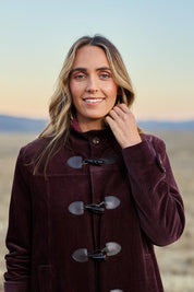 Model Tegan wearing size 10 of the Winter Walk Longline Cord Duffle Coat in colour Aubergine (Purple), from the front, showing the whole outfit