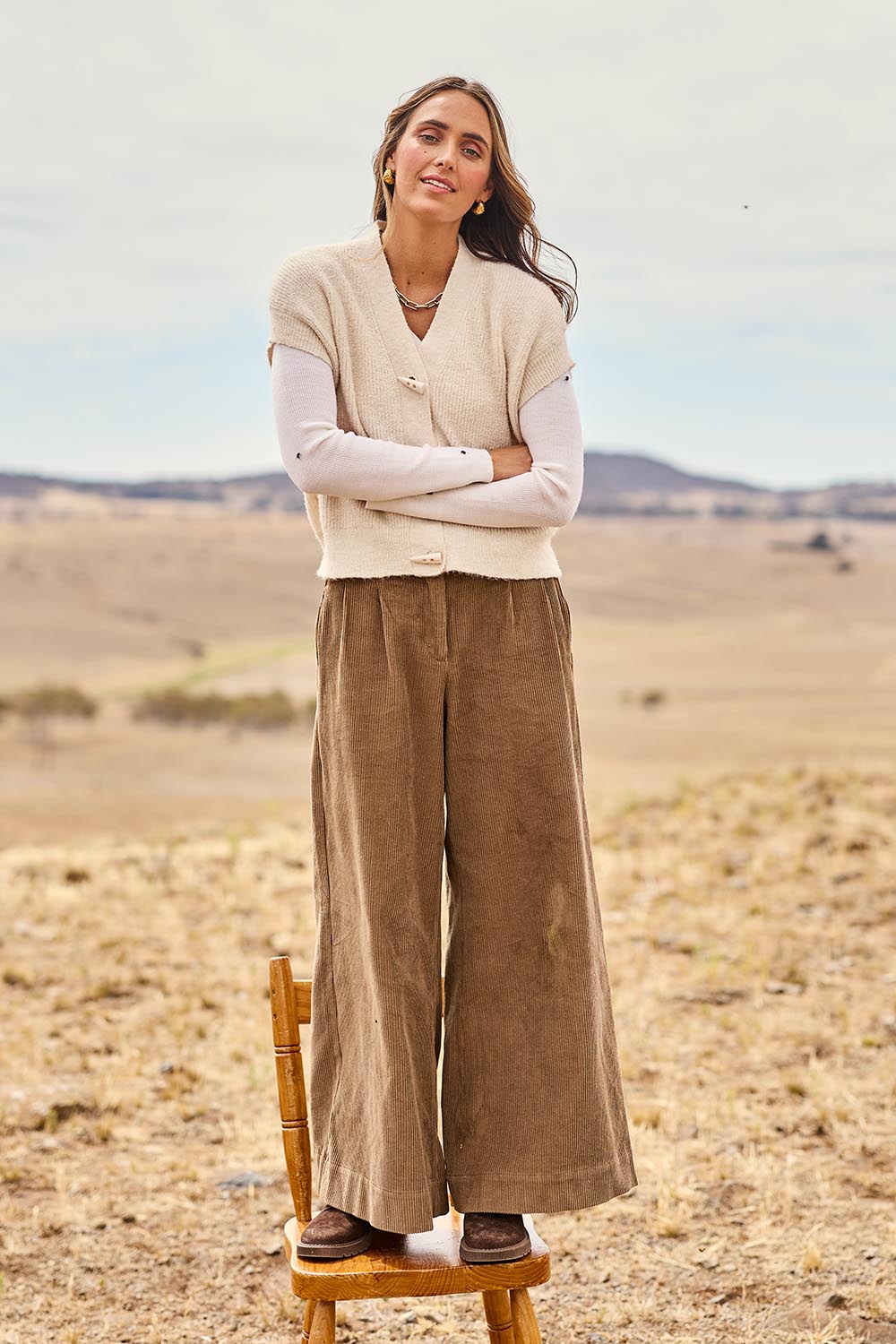 Model Tegan wearing size S of the Found My Friend Recycled Knit Sleeveless Cardi in colour Milk (White), from the front, showing the whole outfit