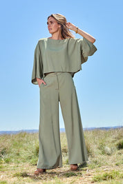 Model Tegan wearing size 10 of the Striding Out Kimono Sleeve Top in colour Thyme (Green), from the front, showing the whole outfit