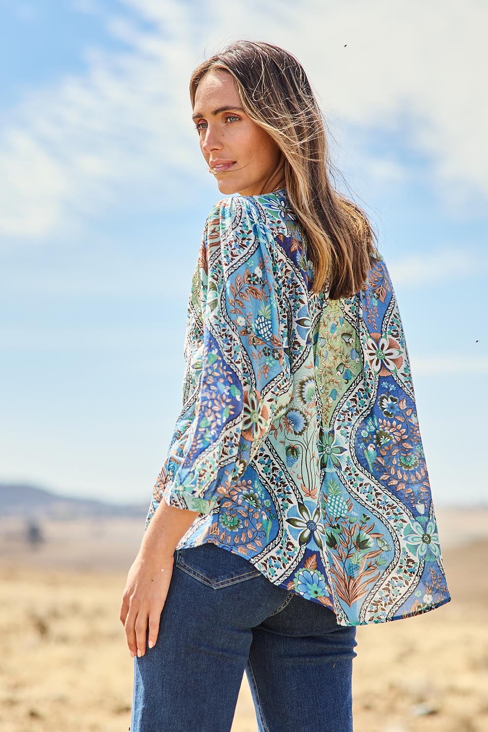 Model Tegan wearing size 10 of the Easy On Me Blouse in colour Bluefolk (Blue), from the front, showing the whole outfit