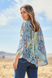 Model Tegan wearing size 10 of the Easy On Me Blouse in colour Bluefolk (Blue), from the front, showing the whole outfit