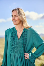 Model Tegan wearing size 10 of the Meadow Meander Smocked Dress in colour Jade (Green), from the front, showing the whole outfit
