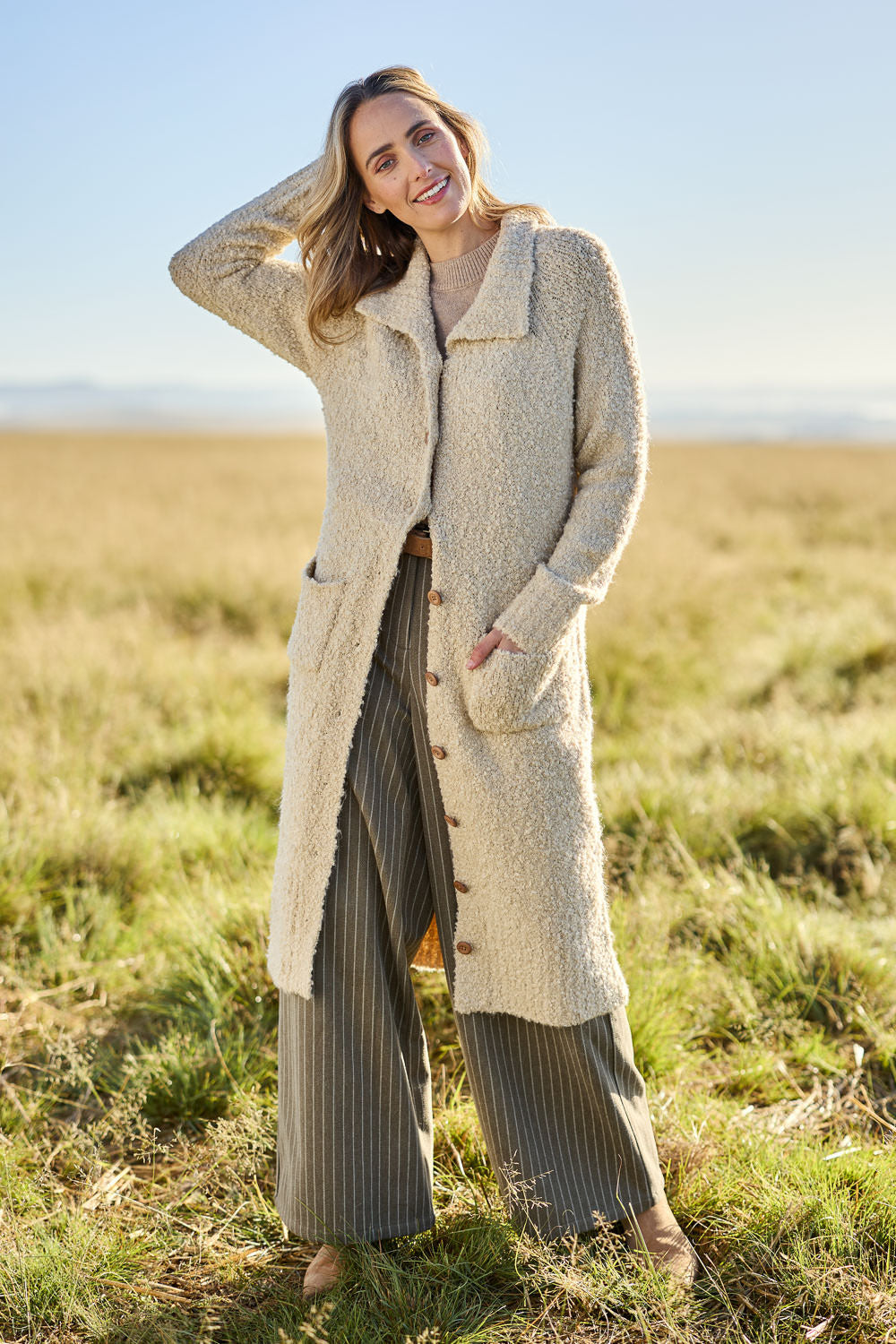 Model Tegan wearing size S of the Sunday Walks Longline Cardi in colour Sand, from the front, showing the whole outfit