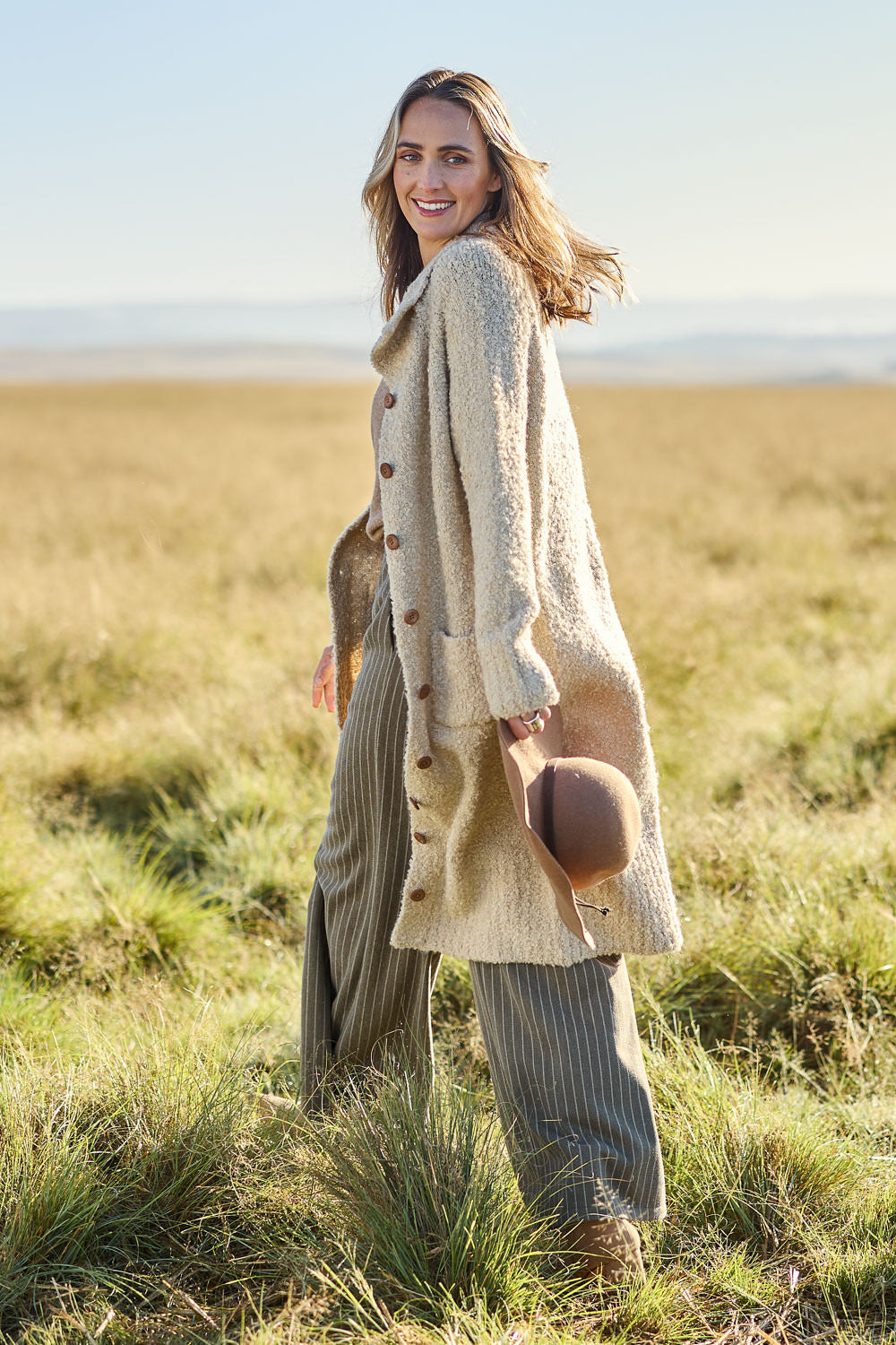 Model Tegan wearing size S of the Sunday Walks Longline Cardi in colour Sand, from the front, showing the whole outfit