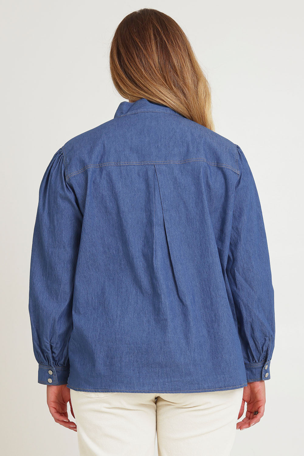 Model Chanel wearing size 16 of the Take A Bow Chambray Blouse in colour Demin (Blue), from the back