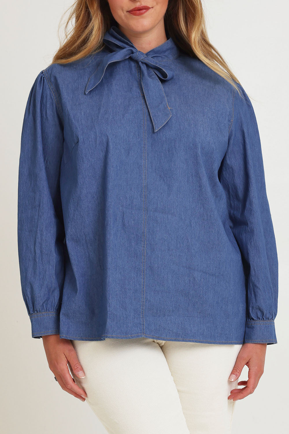 Model Chanel wearing size 16 of the Take A Bow Chambray Blouse in colour Demin (Blue), from the front, cropped image