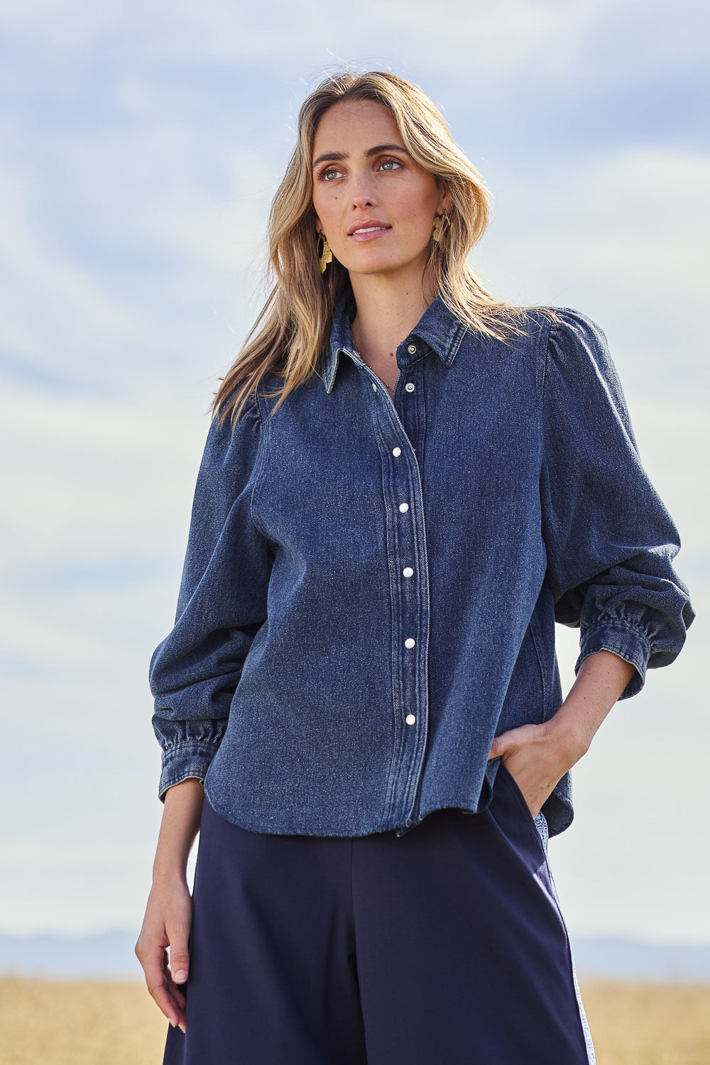 Model Tegan wearing size 10 of the Denim Daze Billow Sleeve Shirt in colour Denim (Blue), from the front, showing the whole outfit