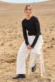 Model Tegan wearing size S of the Love Layer Long Sleeve Knit Top in colour Black (Black), from the front, showing the whole outfit