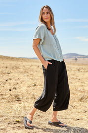 Model Tegan wearing size 10 of the Summer Daze Linen Blend Pull On 3/4 Pant in colour Black (Black), from the front, showing the whole outfit