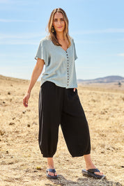 Model Tegan wearing size 10 of the Summer Daze Linen Blend Pull On 3/4 Pant in colour Black (Black), from the front, showing the whole outfit