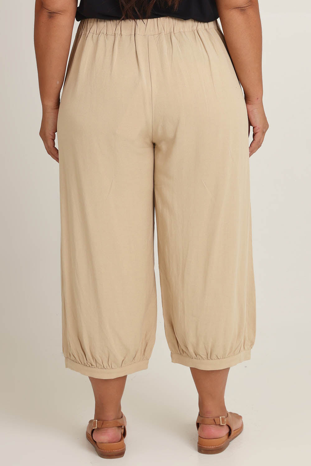 Model Ashleigh wearing size 16 of the Summer Daze Linen Blend Pull On 3/4 Pant in colour Sand, from the back