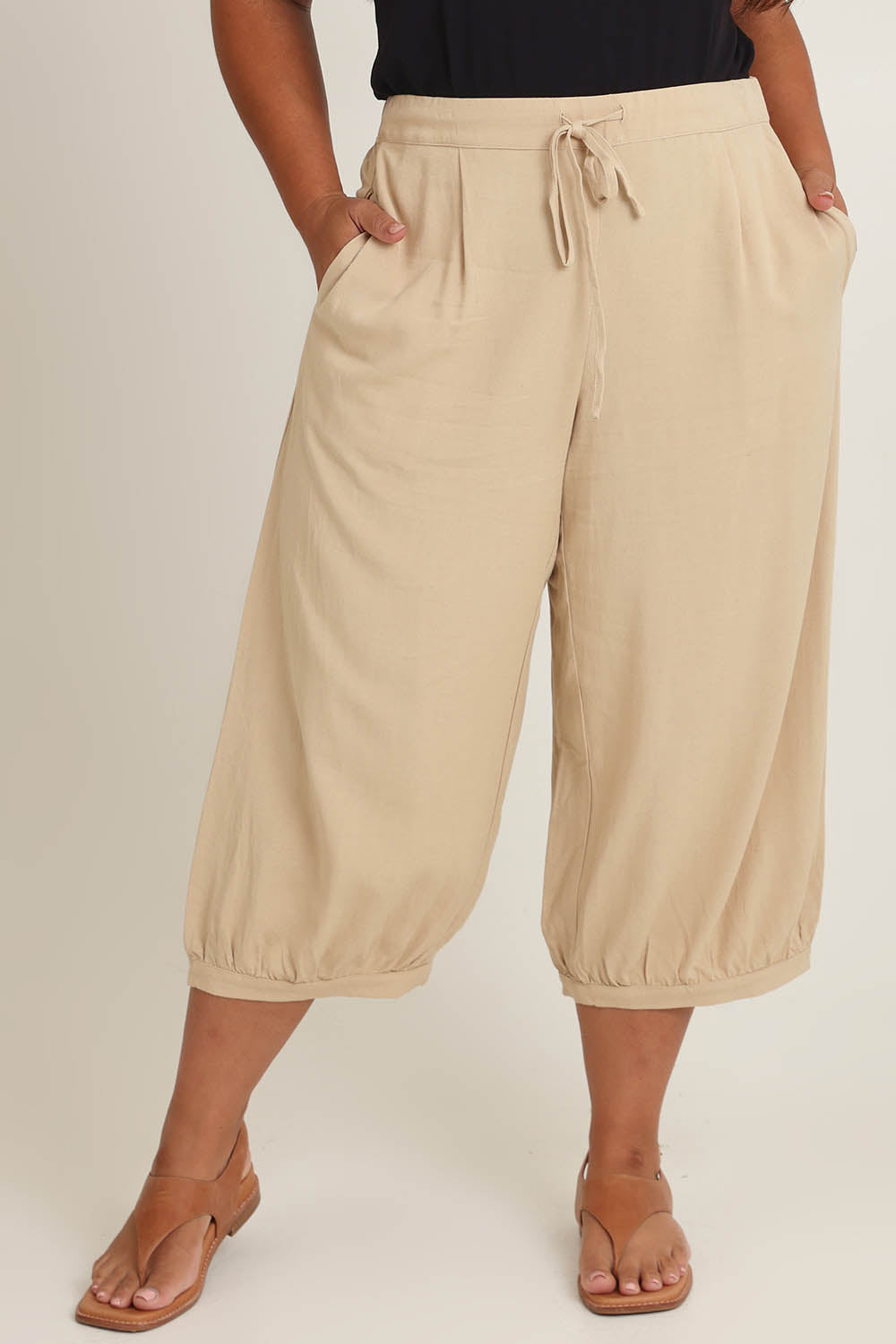 Model Ashleigh wearing size 16 of the Summer Daze Linen Blend Pull On 3/4 Pant in colour Sand, from the front, cropped image