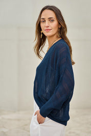 Model Tegand wearing size 10 of the Summer Haze Cardigan – Denim in colour Denim, from an angle
