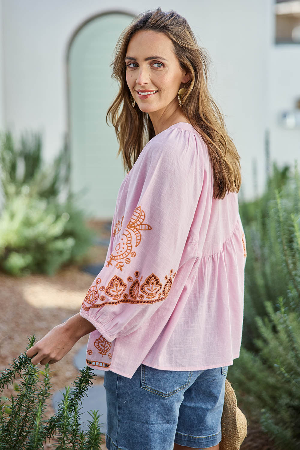 Model Tegand wearing size 10 of the Loving You Is Easy Embroidered Cotton Blouse  - Pinktangerine in colour Pinktangerine, from an angle