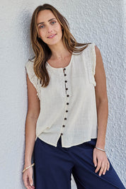Model Tegand wearing size 10 of the Cute As A Button Fringed Tank – Sand in colour Sand, from an angle
