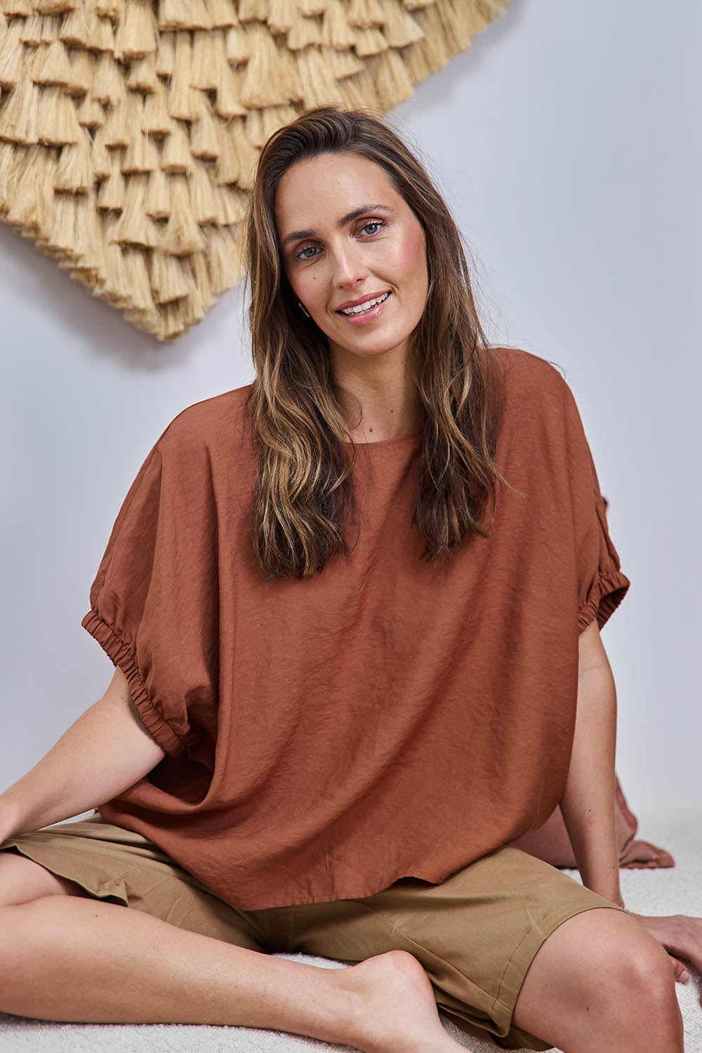Model Tegand wearing size 10 of the Sun Gazer Balloon Sleeve Top – Rust in colour Rust, from an angle