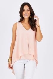 Model Georgia wearing size 10 of the Sugar Snaps Layers Tank in colour PeachyKeen (Pink), from the front, cropped image
