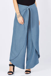 Model Georgia wearing size 10 of the Wrapped In You Pants in colour Denim (Blue), from the front, cropped image