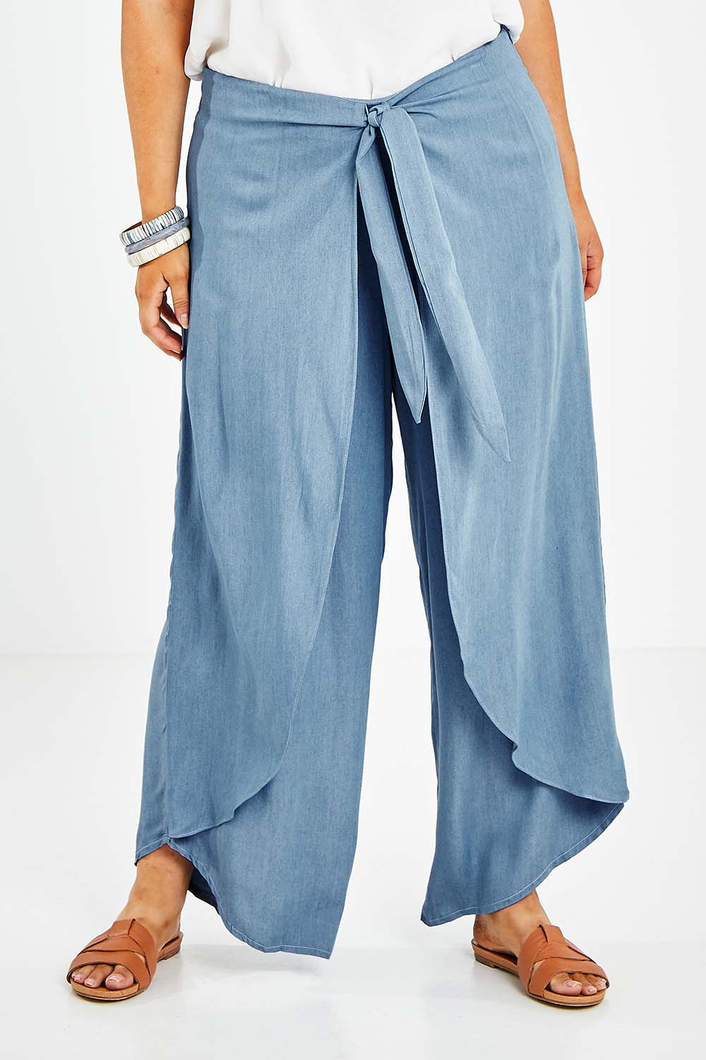 Model Jess wearing size 14 of the Wrapped In You Pants in colour Denim (Blue), from the front, cropped image