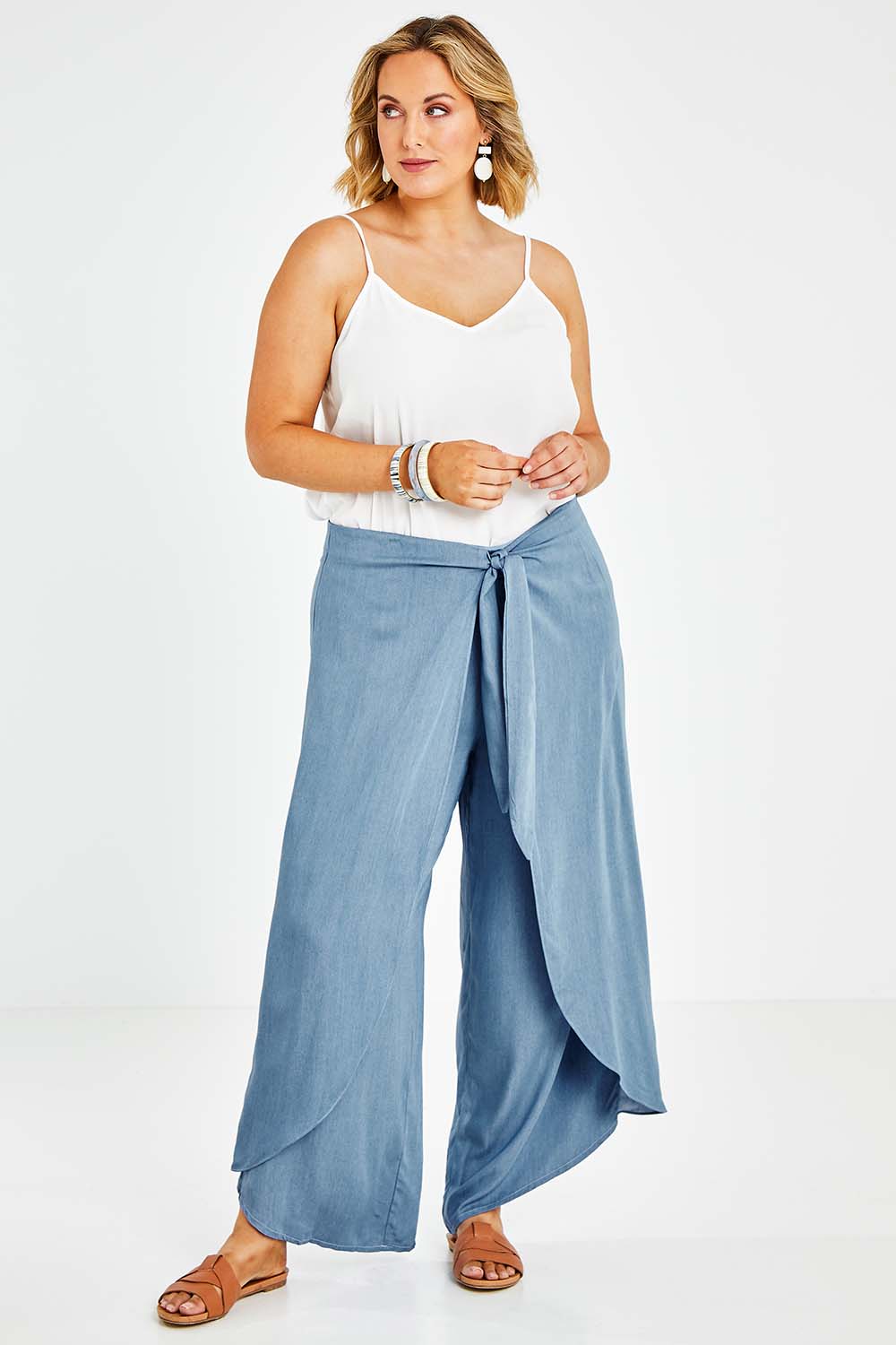 Model Jess wearing size 14 of the Wrapped In You Pants in colour Denim (Blue), from the front, showing the whole outfit