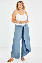 Model Jess wearing size 14 of the Wrapped In You Pants in colour Denim (Blue), from the front, showing the whole outfit